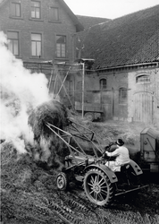 Mitten auf dem Hof verlädt der Landwirt Mist mit Hilfe des Frontladers an seinem Traktor. 