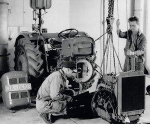 In der Prüfwerkstatt bauen zwei Mitarbeiter den kompletten Motor eines Schleppers aus, um ihn zu untersuchen.